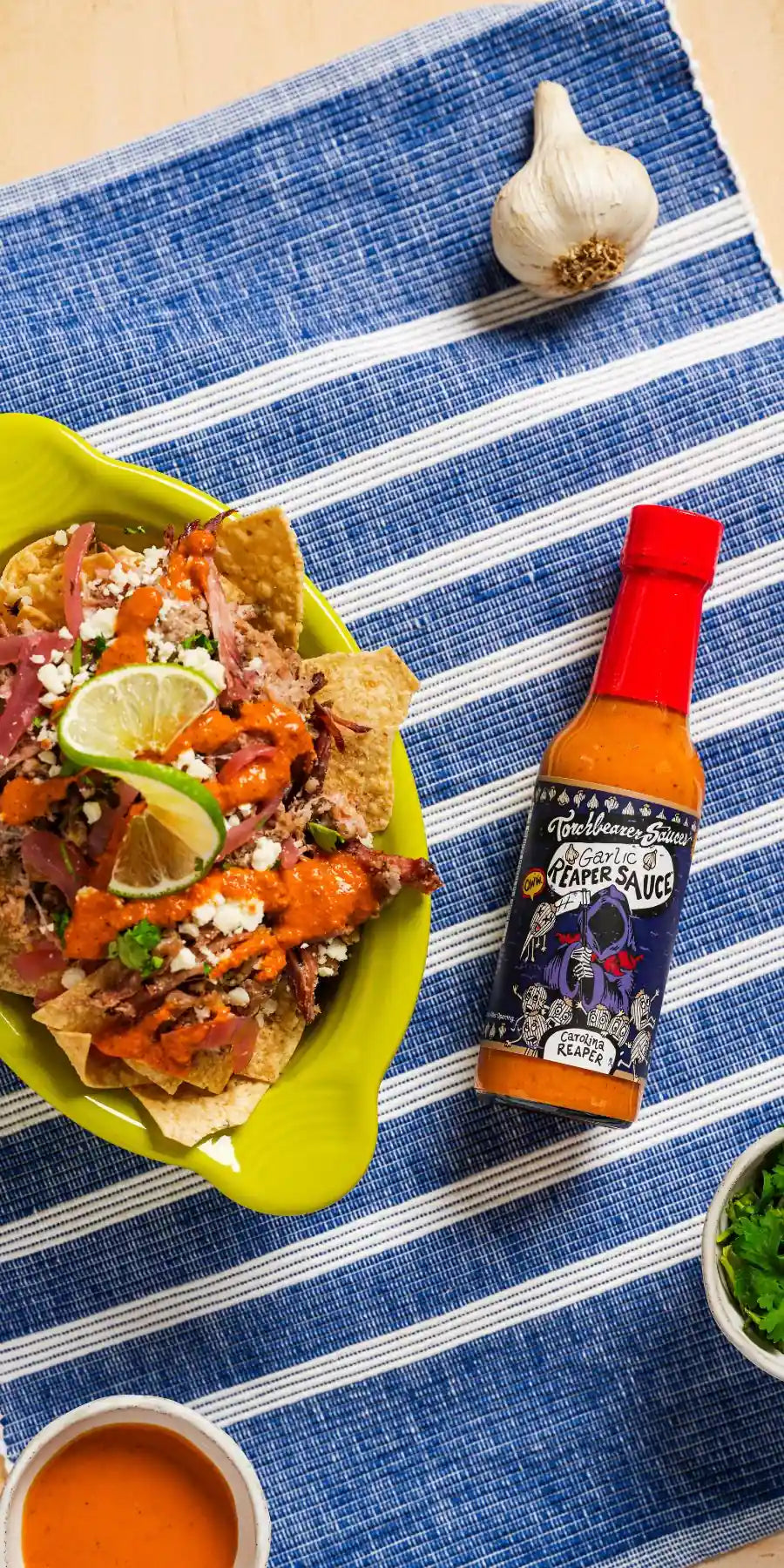 Taco bowl with a bottle of Garic Reaper hot sauce on a blue striped tablecloth